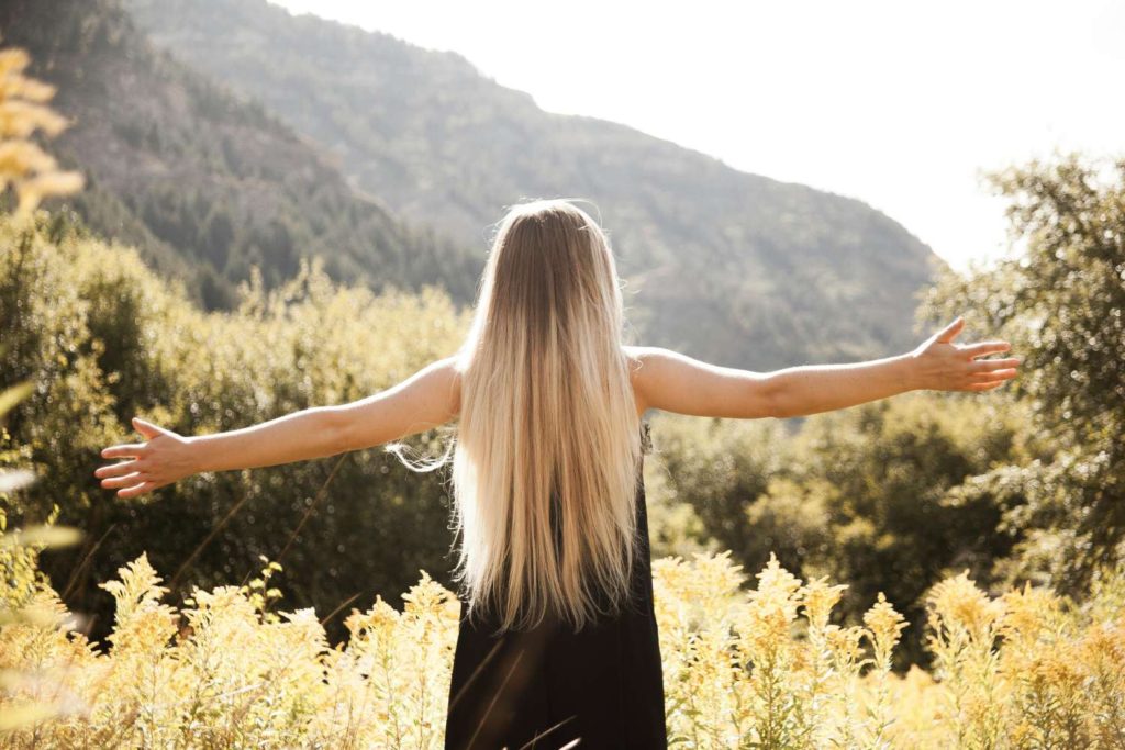 back view of a woman in a field holding her arms out to the sides